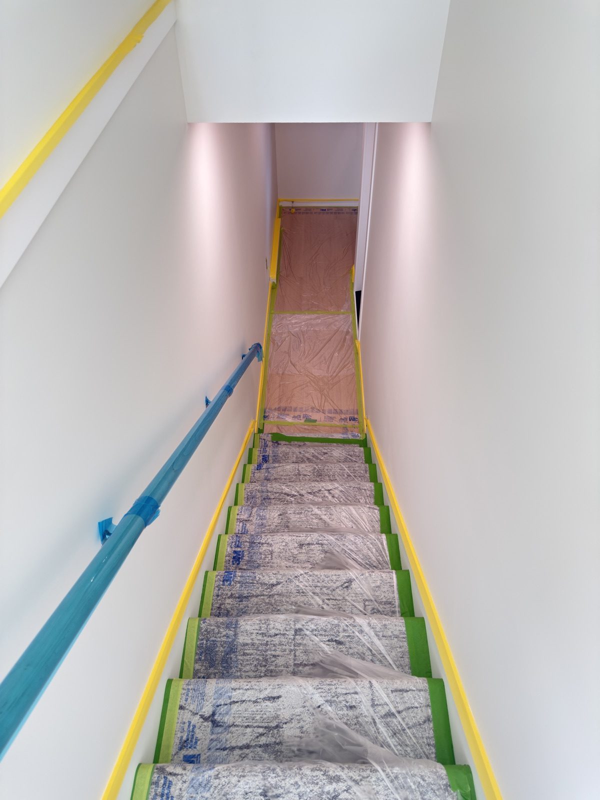 Finished stairs and handrail covered in plastic and tape before the seal