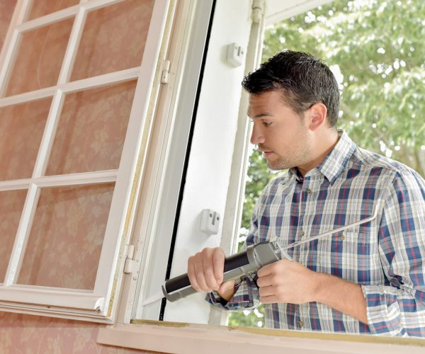 man caulking up window